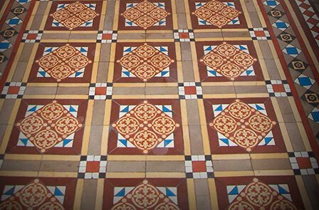 A restored Victorian hallway showcasing vibrant geometric encaustic floor tiles in a London period property.